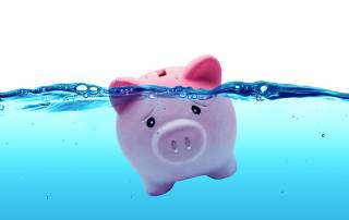 Ein Sparschwein schwimmt im Wasser und droht unterzugehen | Immobilie verkaufen