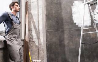 Ein Bauarbeiter steht in einem Raum der renoviert wird mit einer Leiter - Renovieren, Sanieren, Modernisieren