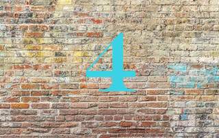 Die Zahl Vier in blau vor einer braun-roten Backsteinwand - Kleine Wohnfläche