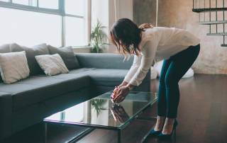 Eine Frau dekoriert das Wohnzimmer eines Hauses mit Home Staging, um die Immobilie auf eine Besichtigung mit Kaufinteressenten vorzubereiten | Home Staging