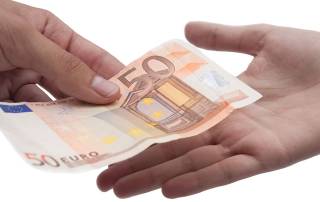 Großansicht zweier Hände: Eine Person überreicht der anderen Geld