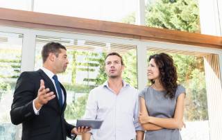 EIn Makler und ein Pärchen beim Verkauf