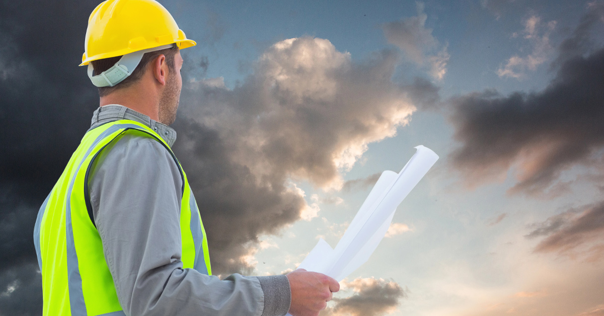 ein Bauarbeiter vor einer Gewitterwand; als symbol für eine Krise im Neubau