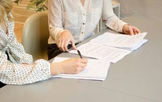 Eine Immobilienkäuferin unterzeichnet den Kaufvertrag bei einer Notarin | Immobilienverkauf