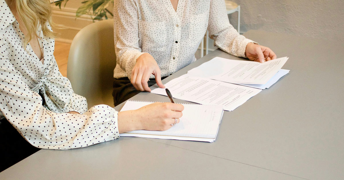 Eine Immobilienkäuferin unterzeichnet den Kaufvertrag bei einer Notarin | Immobilienverkauf