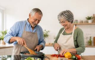 Älteres Paar kocht gemeinsam in einer hellen, modern gestalteten Küche – ein Beispiel für komfortables und barrierefreies Wohnen im Alltag. | Barrierfreier Umbau